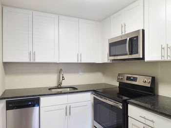 A kitchen with white cabinets and black countertops
